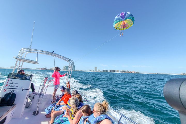 a group of people on a boat with two parasailers behind them