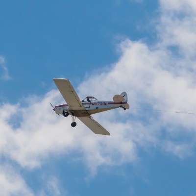 a small airplane flying through a cloudy blue sky