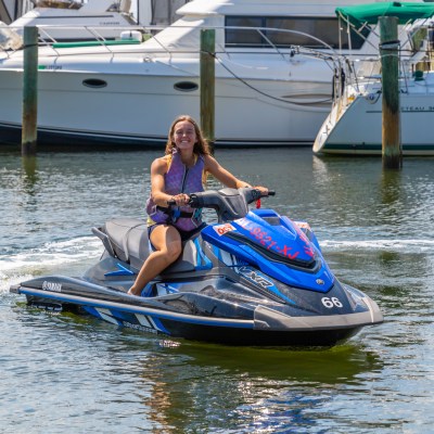 a woman riding on the back of a boat in the water