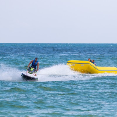 a group of people in a banana boat being pulled by a jet ski