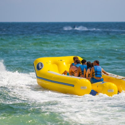 a group of people in a banana boat being pulled by a jet ski