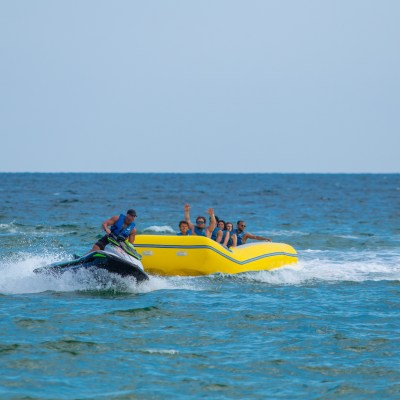 a group of people in a banana boat being pulled by a jet ski