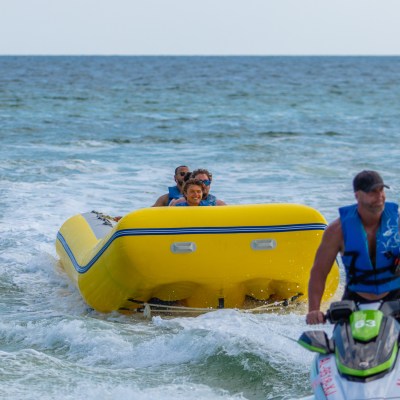 a group of people in a banana boat being pulled by a jet ski